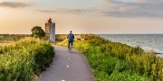 Meisje fietsen naar vuurtoren De Ven bij Edam tijdens zonsondergang in Noord-Holland in Nederland