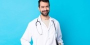 Jonge blanke man die een doktersjas draagt, stethoscoop om heeft ​​en een map vasthoudt op een blauwe achtergrond