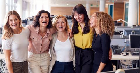 Lachende vrouwelijke collega's die samenwerken in een modern kantoor