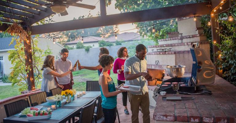 vrienden eten samen onder overkapping in de tuin
