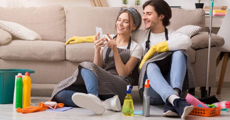 gelukkig stel kijkt tijdens het schoonmaken op de telefoon