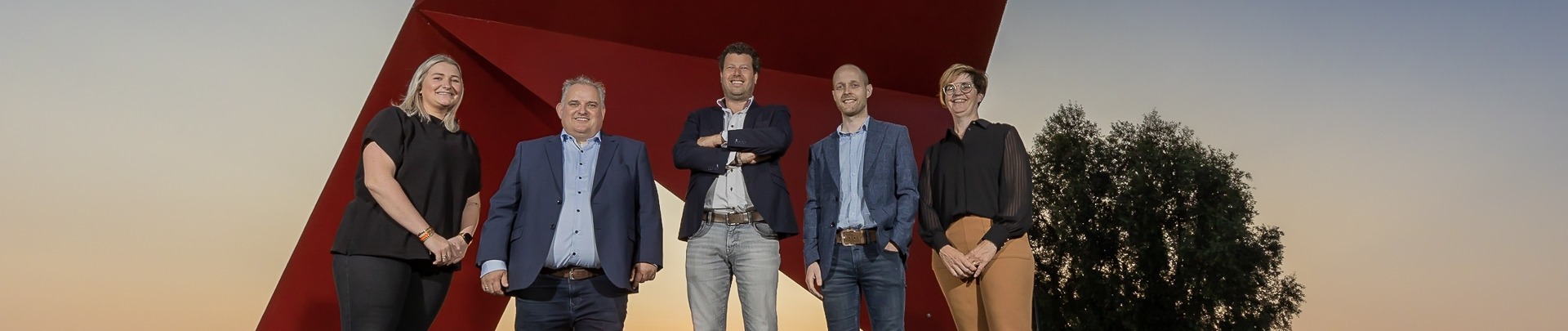 Het team van JacobsVerzekerd bij ondergaande zon voor een kunstwerk in Venlo