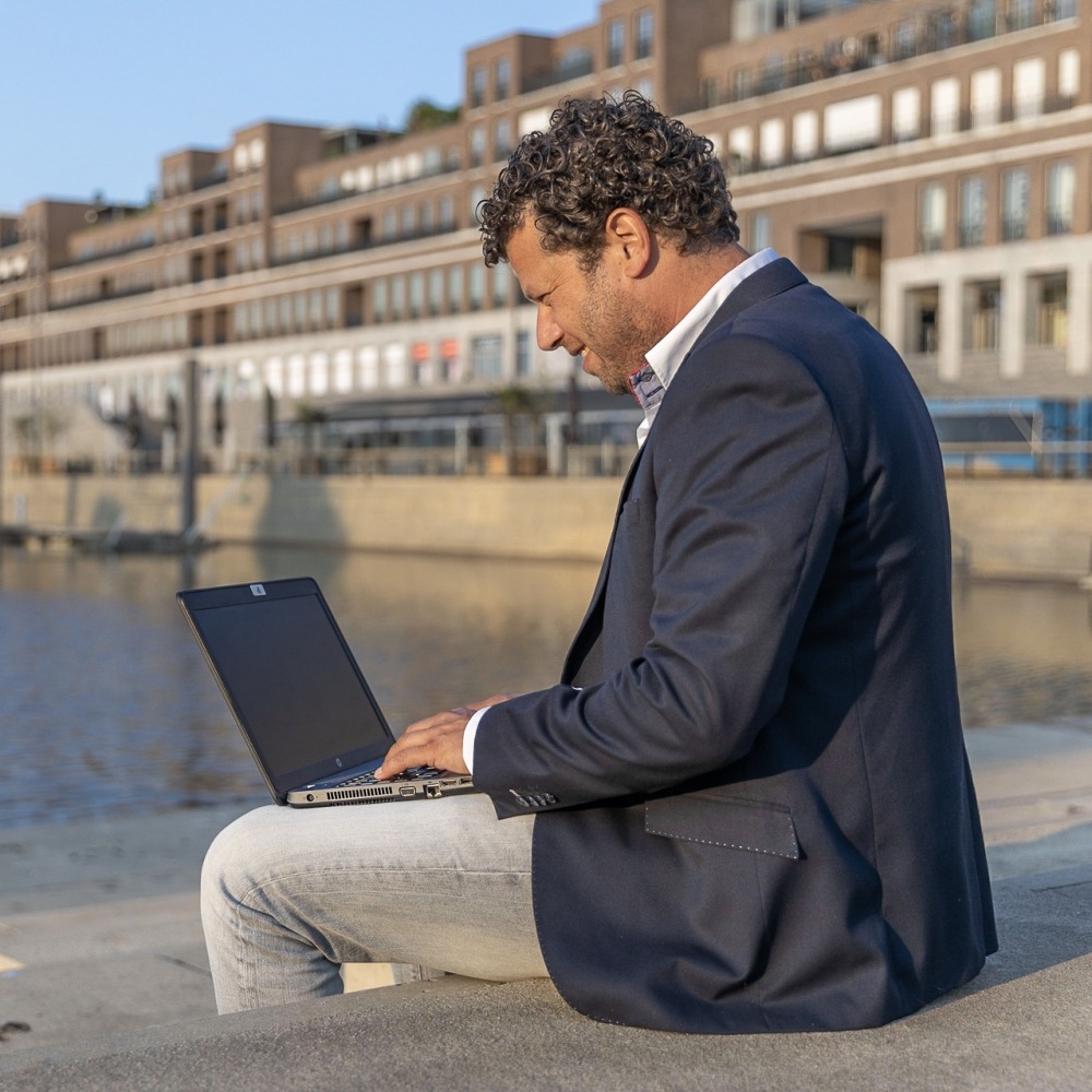 Tom Pansters van JacobsVerzekerd met een laptop op schoot en op de achtergrond Venlo