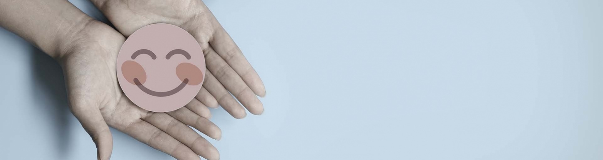 Handen welke een met roze papier gesneden blije glimlach dragen op blauwe achtergrond